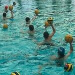 Players practicing with water polo balls.